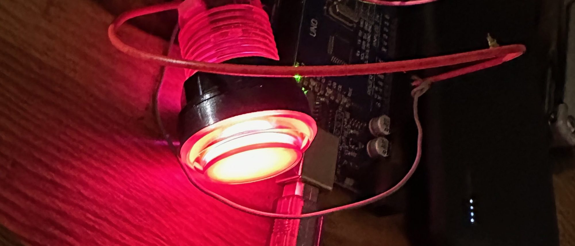 Ein Knopf leuchtet rot in der abgedunkelten Werkstatt